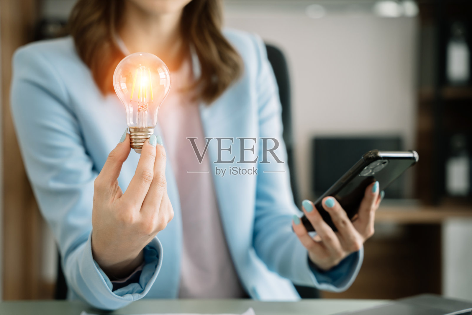 拿着电灯泡的女商人，在办公室里用创新的技术和创造力带来了新的想法。照片摄影图片