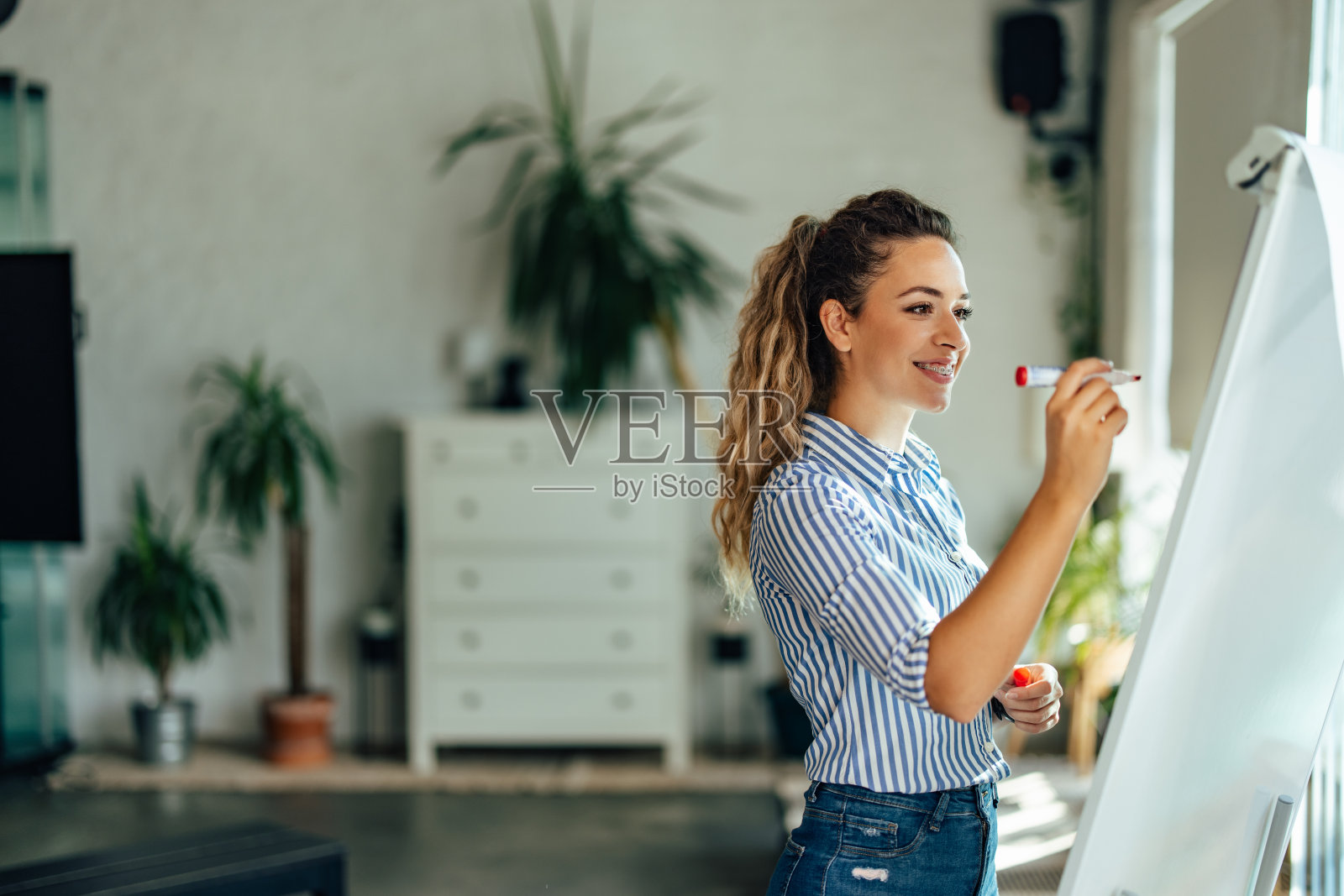 积极的女孩正在用白板和记号笔为公司的新项目制定计划。照片摄影图片