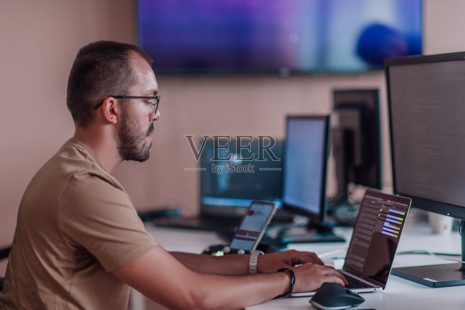 一个程序员坐在办公室里勤奋地测试智能手机应用程序。照片摄影图片