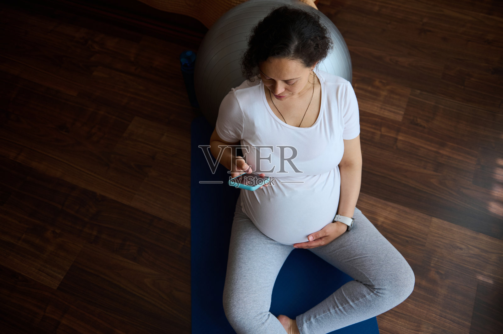 孕妇产前健身后在运动垫上使用智能手机，浏览手机应用，瑜伽练习后休息照片摄影图片