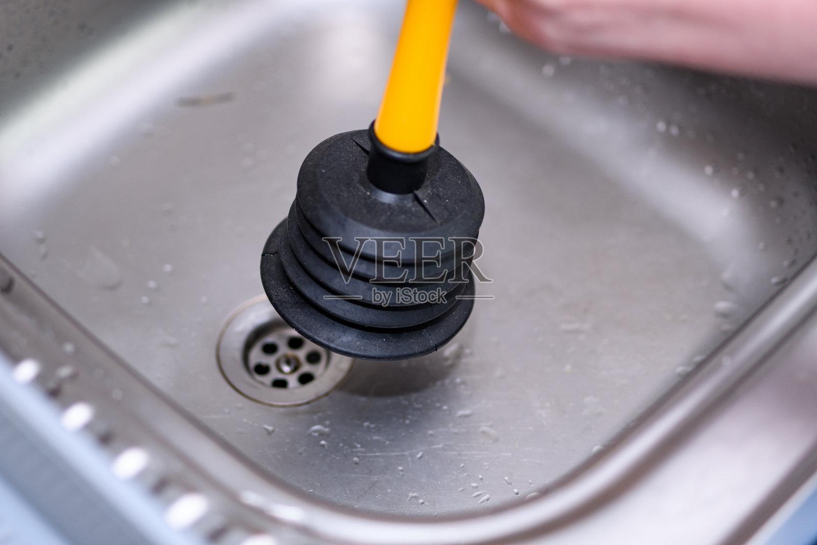 厨房里一个堵塞的水槽和一个橡胶柱塞来疏通排水管照片摄影图片