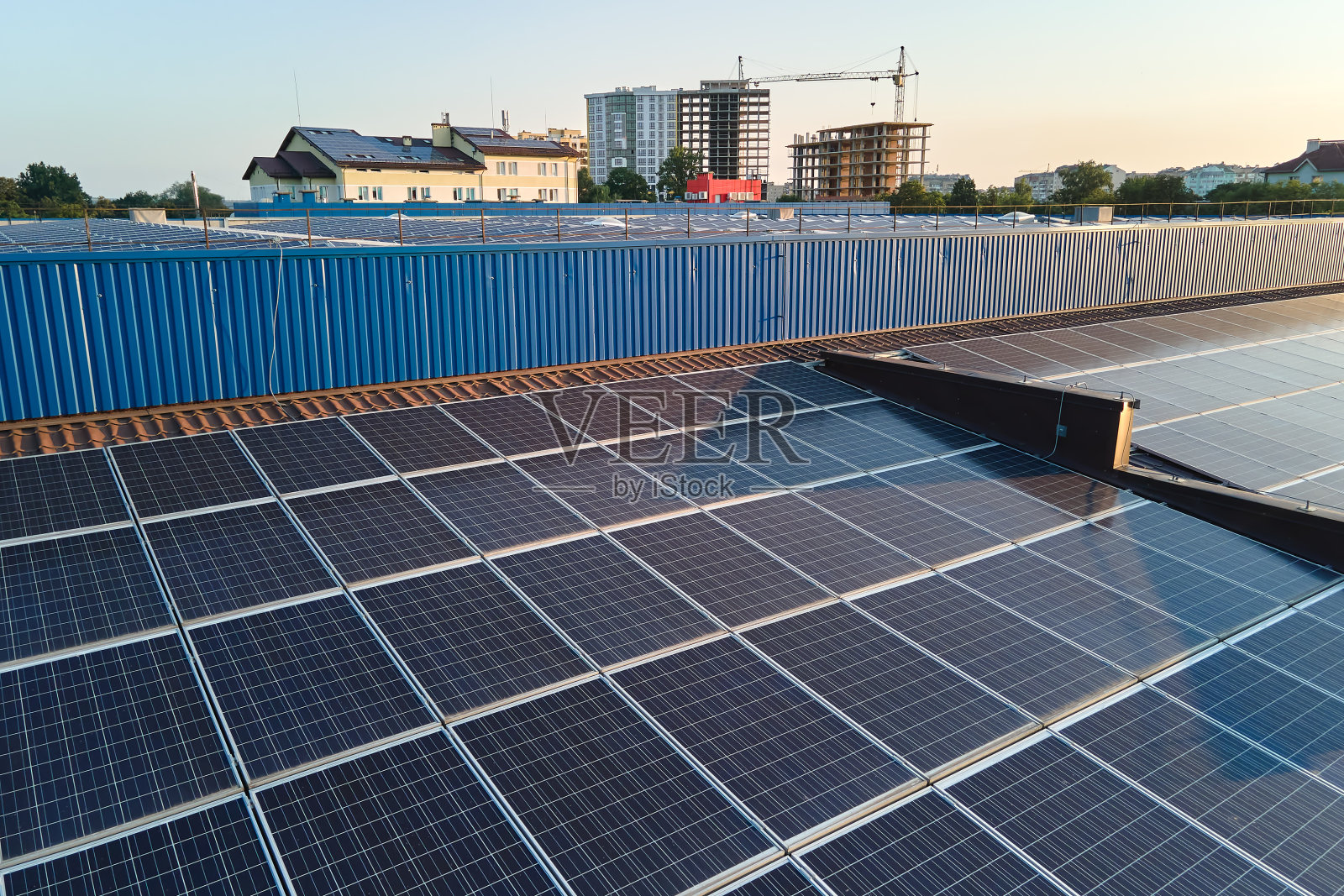 鸟瞰安装在工业建筑屋顶上的蓝色光伏太阳能板，产生绿色生态电力。生产可持续能源的理念照片摄影图片