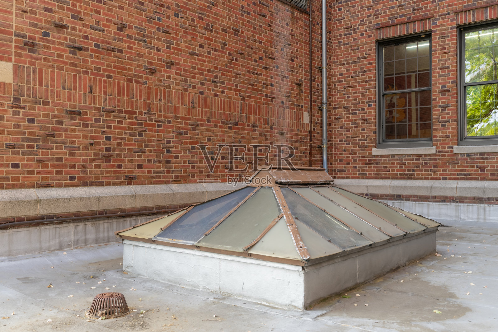 旧的，老式的金属框架双斜天窗上的平面商业，工业，或学校的屋顶。照片摄影图片