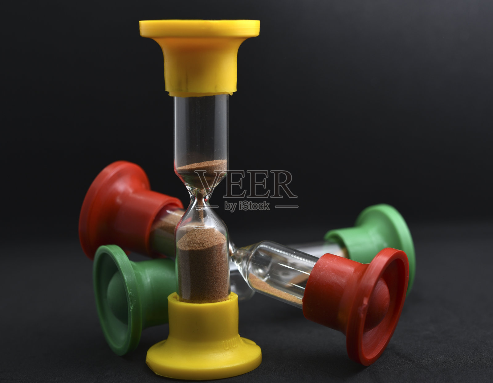 黑色背景上的彩色玻璃沙漏。老式的沙漏。照片摄影图片