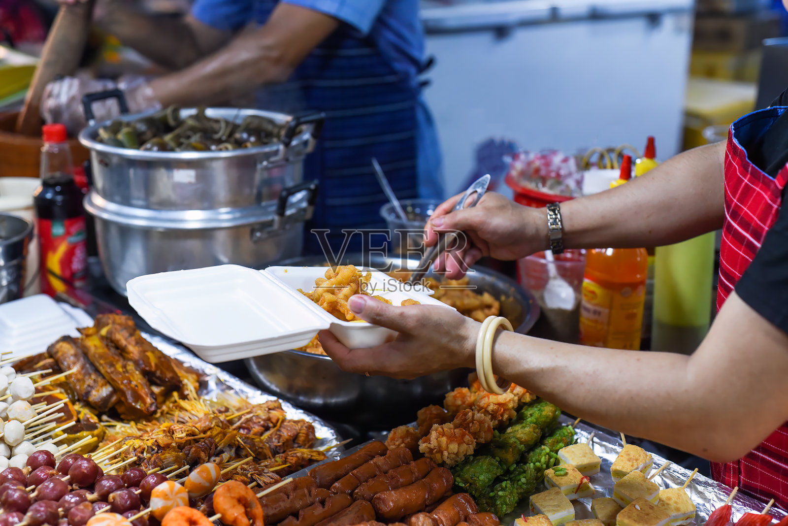 越南女子在越南夜市上用塑料盒盛着辣椒的鸡爪照片摄影图片