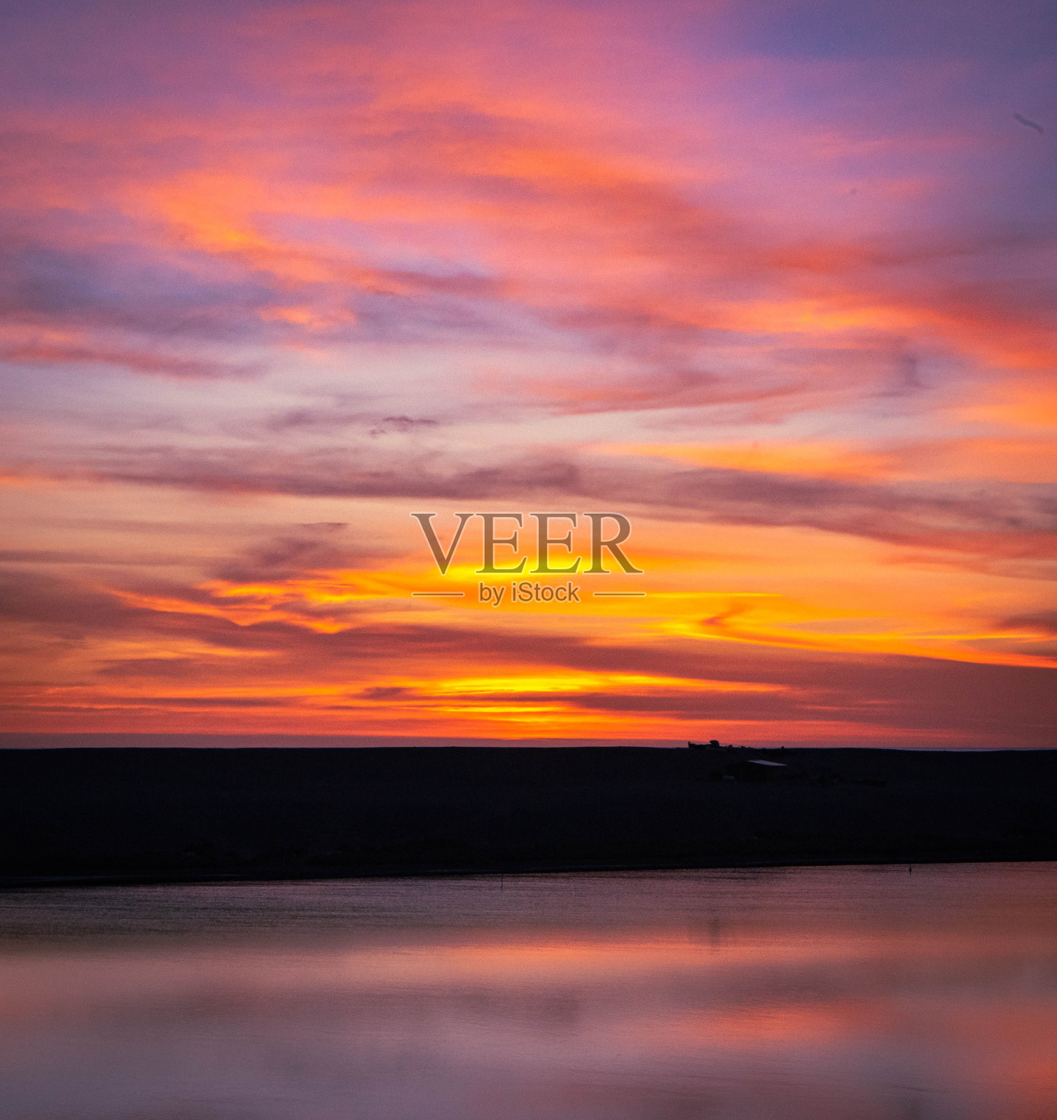 地平线上平静的水面上令人惊叹的日落照片摄影图片