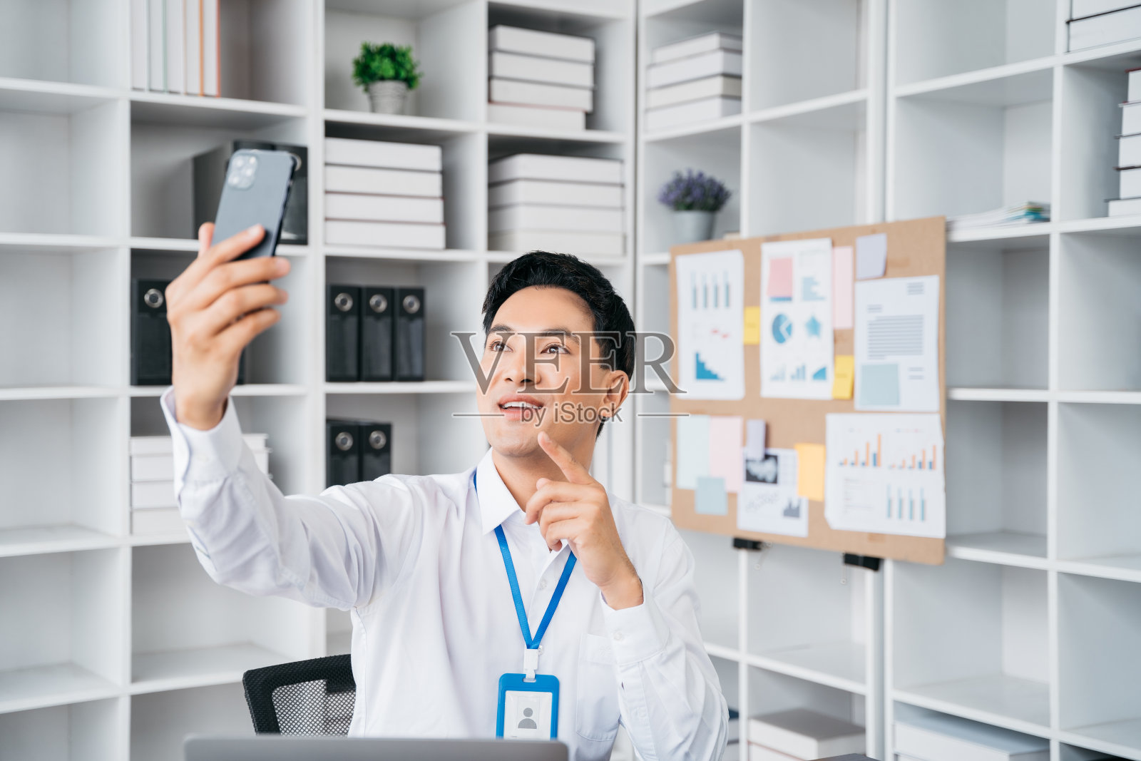 快乐的商人拿着手机看着屏幕挥手视频呼叫朋友在线移动聊天应用使用智能手机视频聊天应用。照片摄影图片