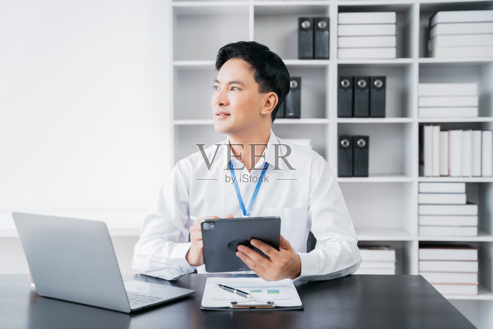 商人在家办公，有平板电脑和笔记本电脑，桌上有文件。照片摄影图片