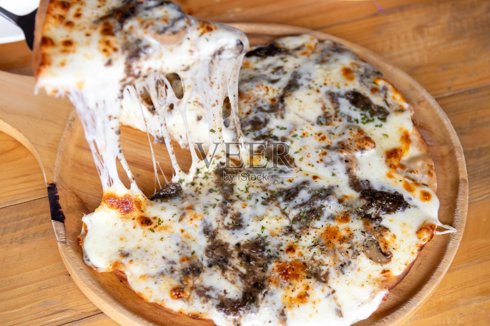 披萨黑松露和奶酪融化在木制的披萨盘上。照片摄影图片