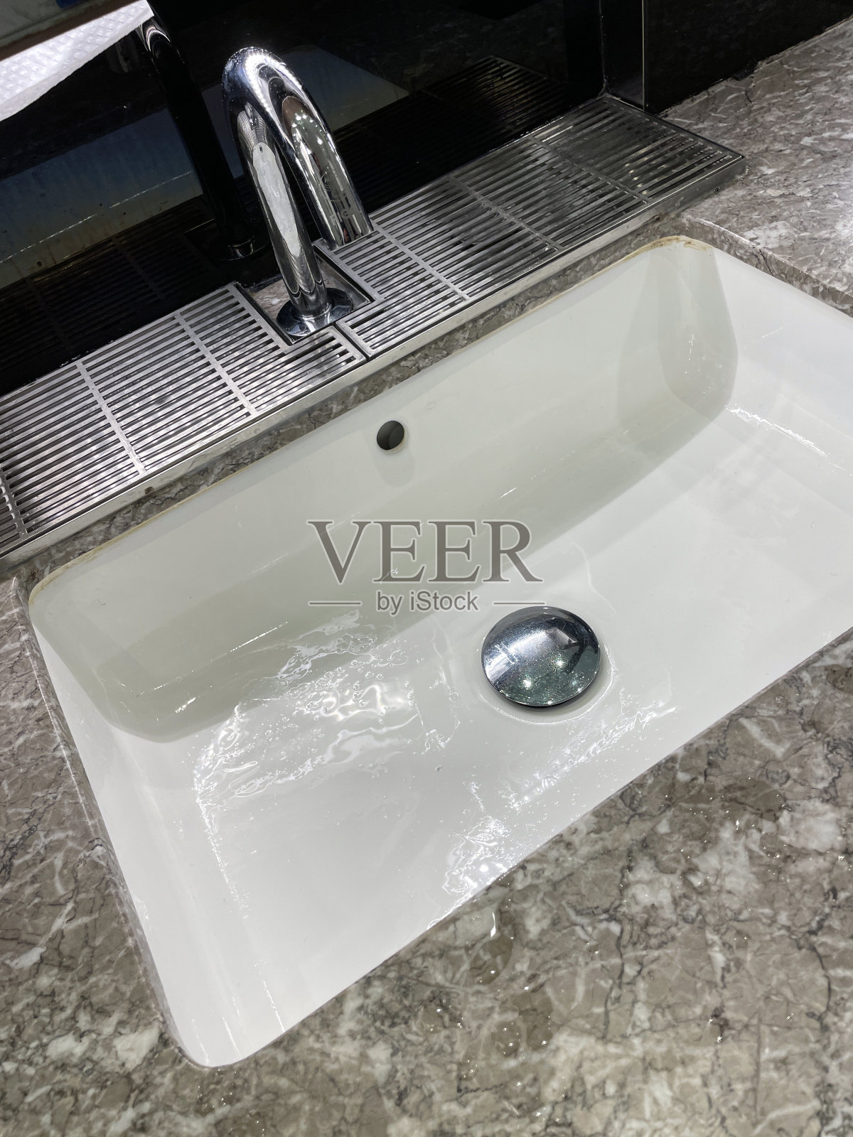 个人特写形象，陶瓷矩形水槽融入公共卫生间大理石效果柜台，墙镜，高架视野，聚焦前景照片摄影图片