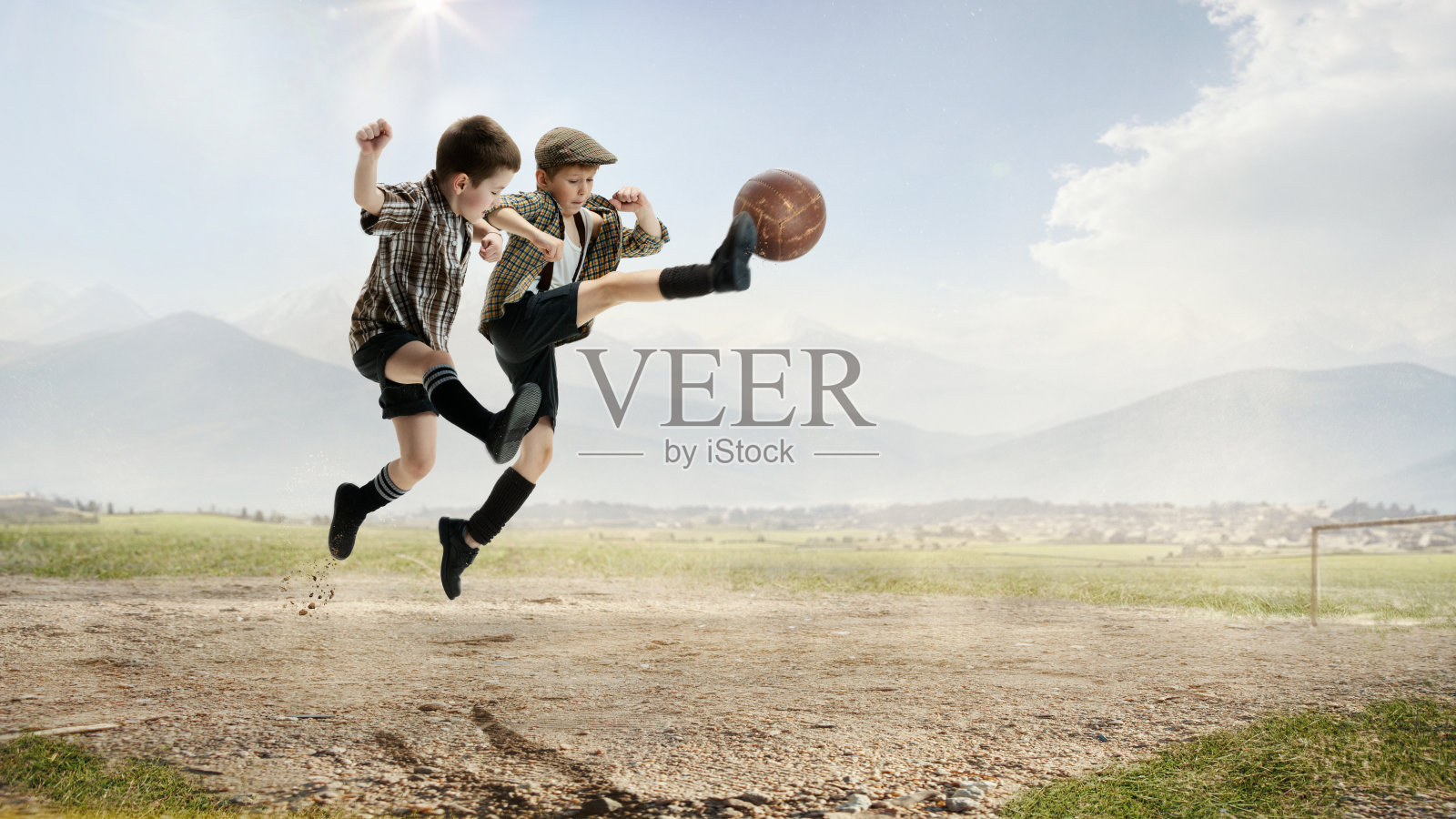 活泼、开朗的小男孩，孩子们穿着复古风格的衣服，在户外踢着跳球，踢着白天的足球照片摄影图片