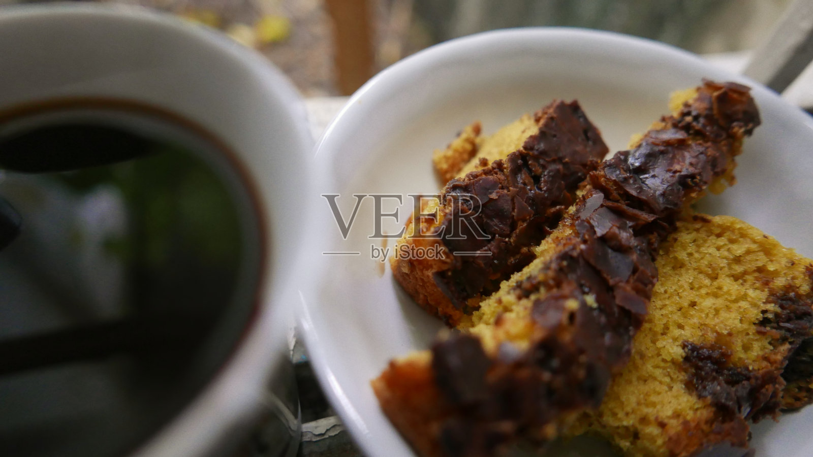 一杯咖啡和一块蛋糕。窗户上有巧克力的胡萝卜蛋糕。咖啡在窗户上。甜点准备好了。早餐时间照片摄影图片