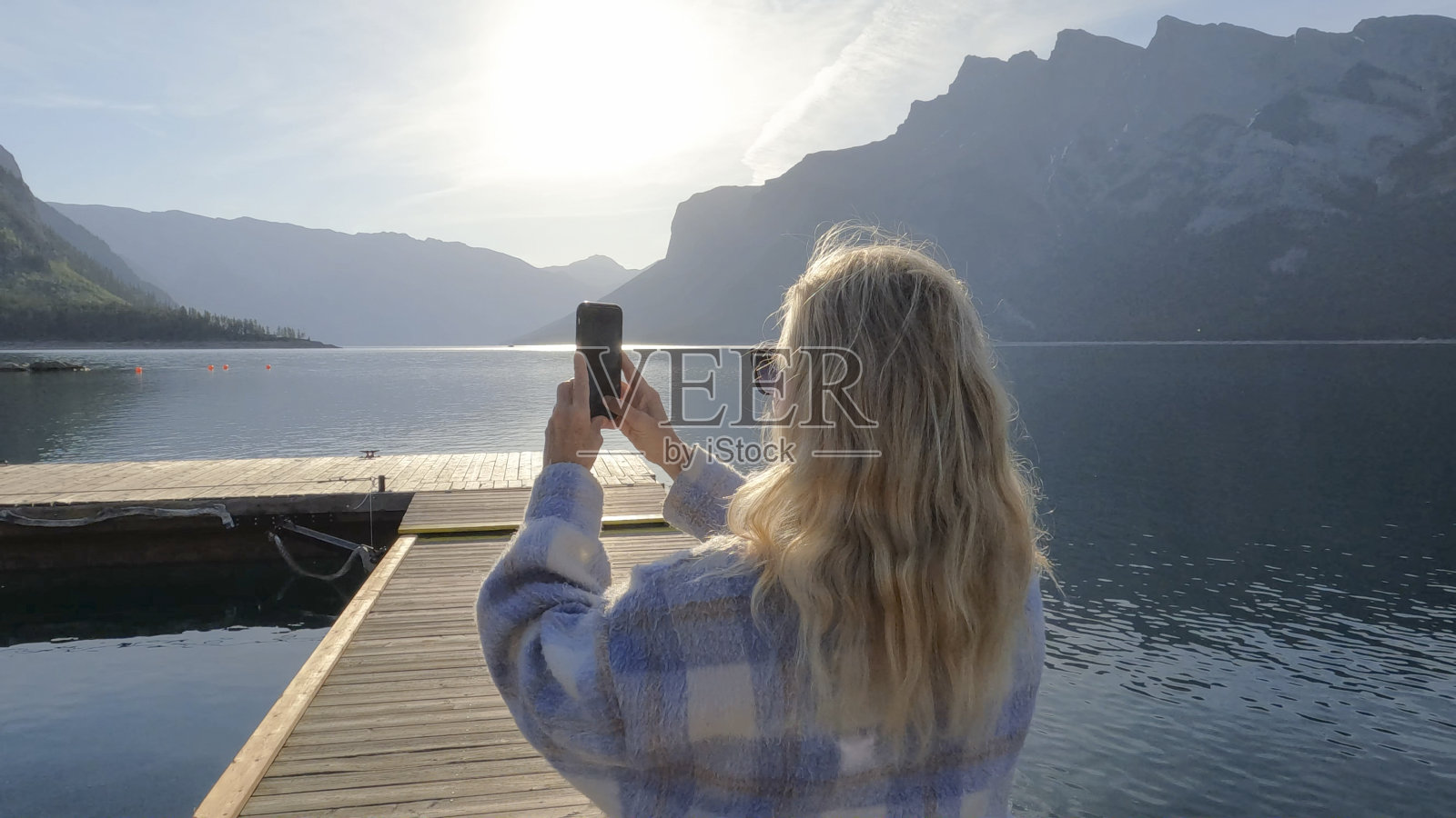 一位老妇人沿着木制的湖码头散步照片摄影图片