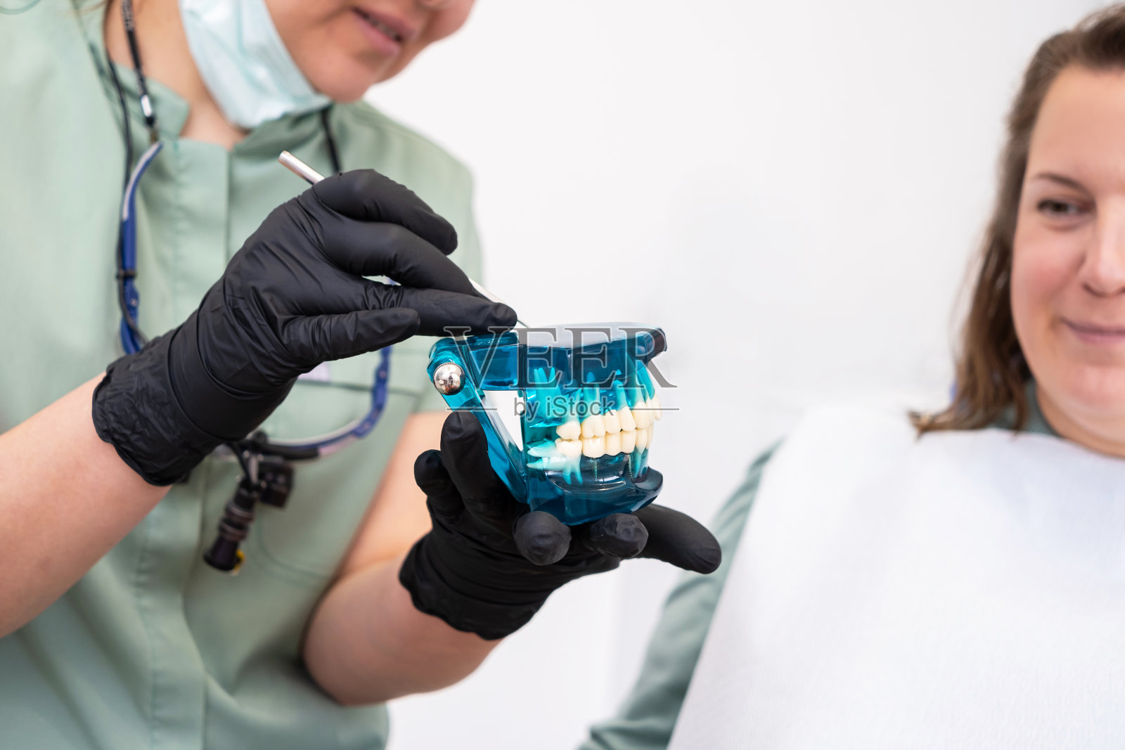 牙医，在正畸检查时，拿着一个描绘上颚和下颚的牙科模型。照片摄影图片