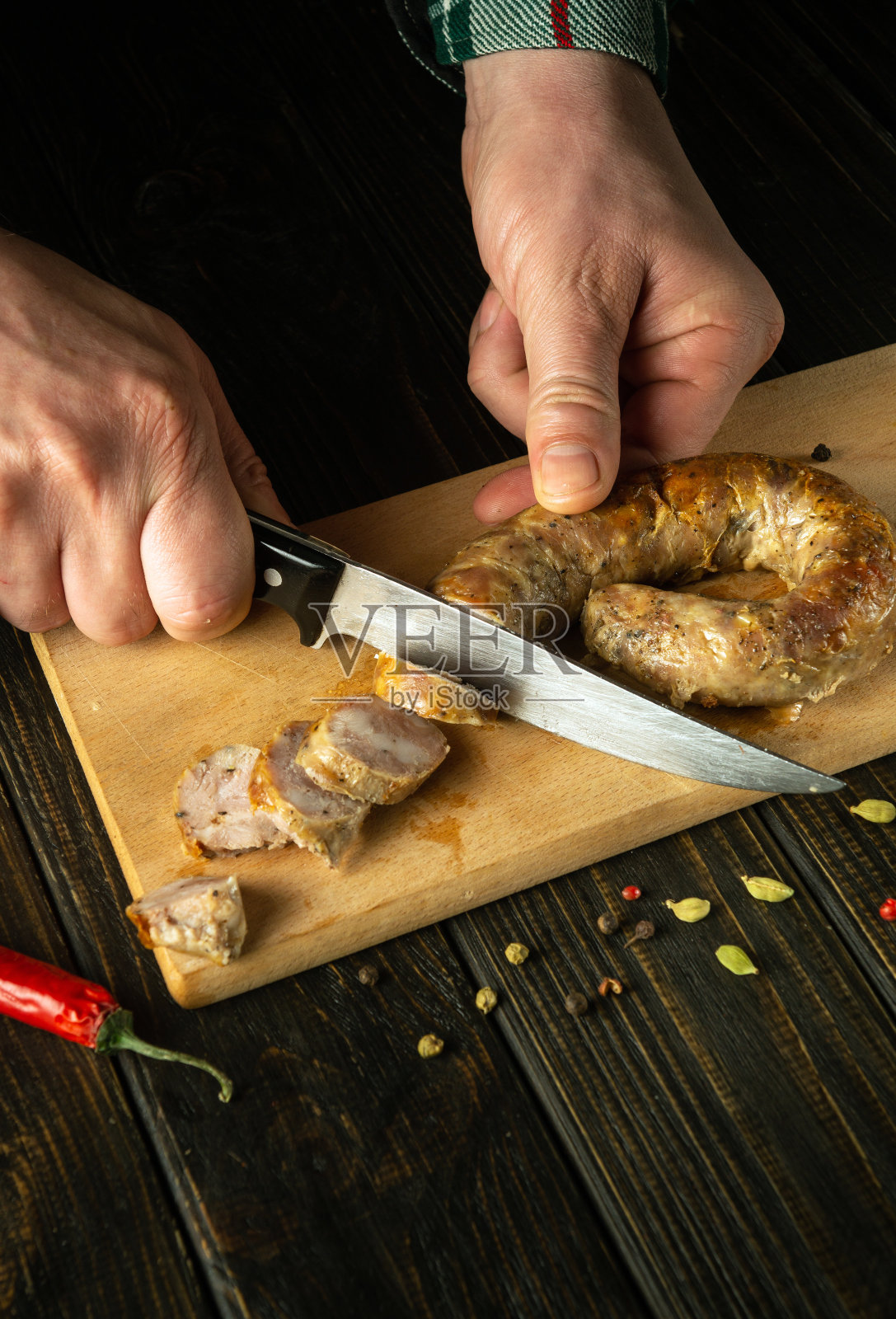 厨师的手拿着刀在切菜板上切烤猪肉香肠，这是一顿美味的午餐。泰国北部国菜照片摄影图片