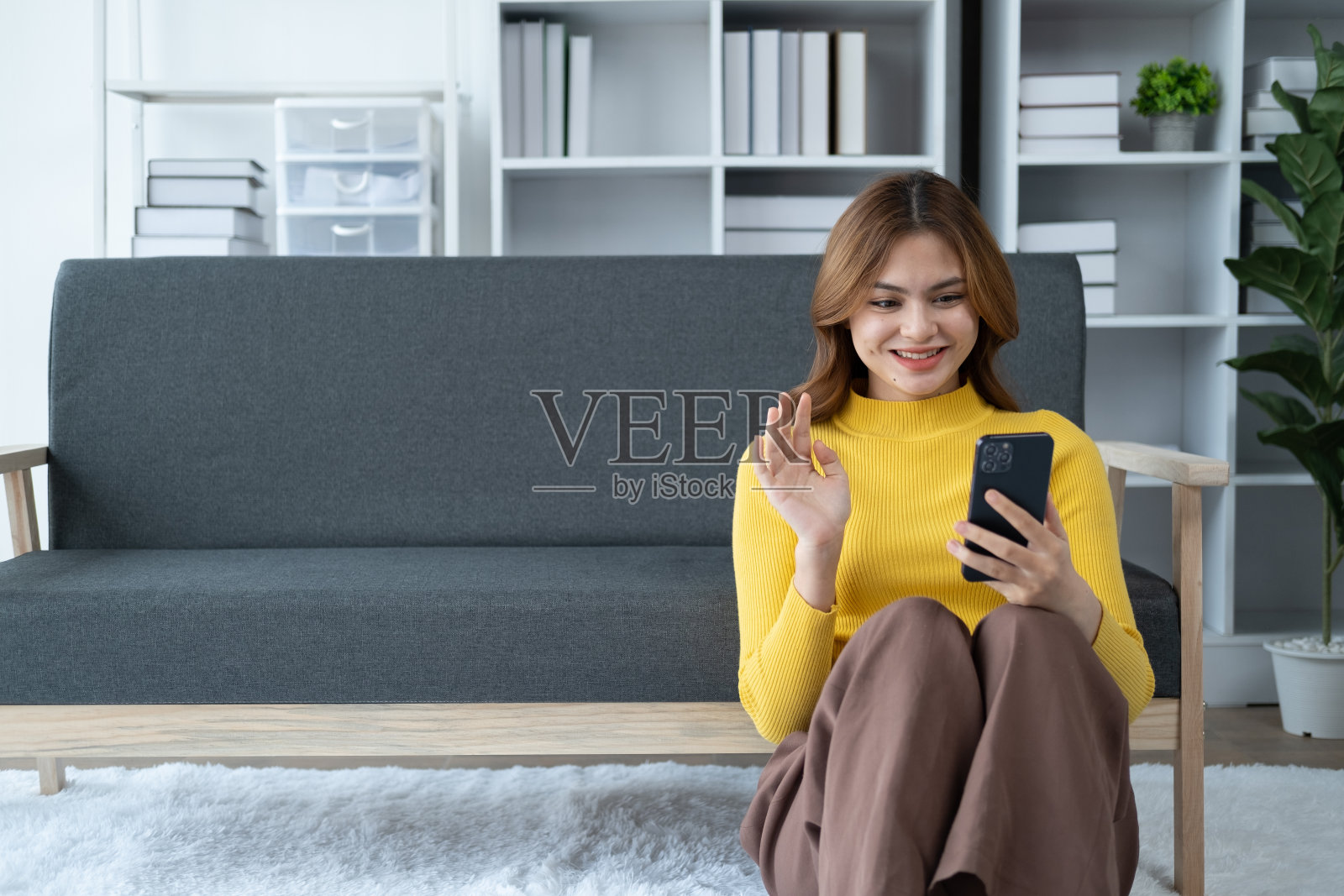 小女孩坐在客厅的沙发上和家人视频通话。照片摄影图片