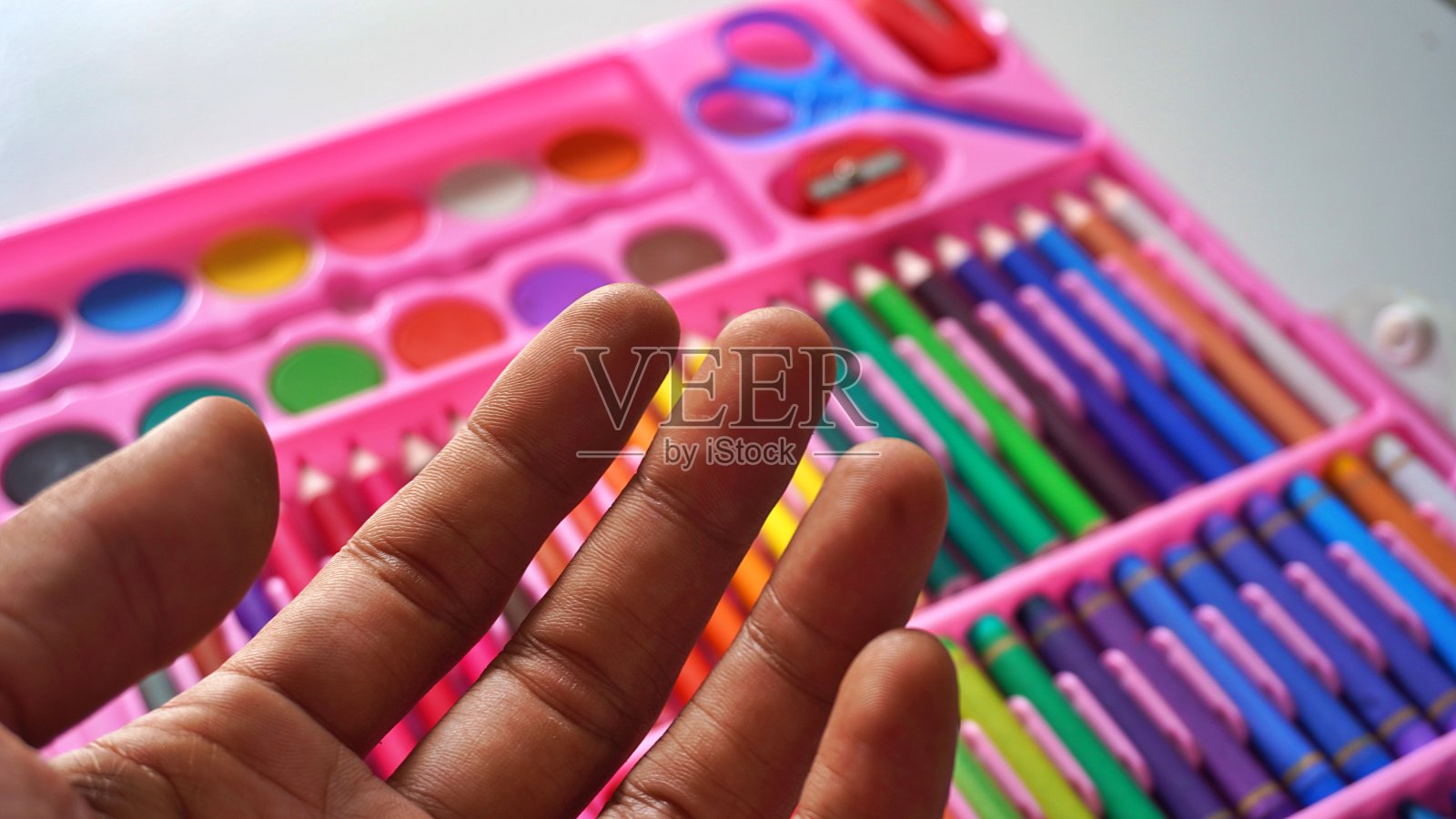 手持彩色铅笔或彩色粉彩整齐地安排一组彩色铅笔的背景照片摄影图片