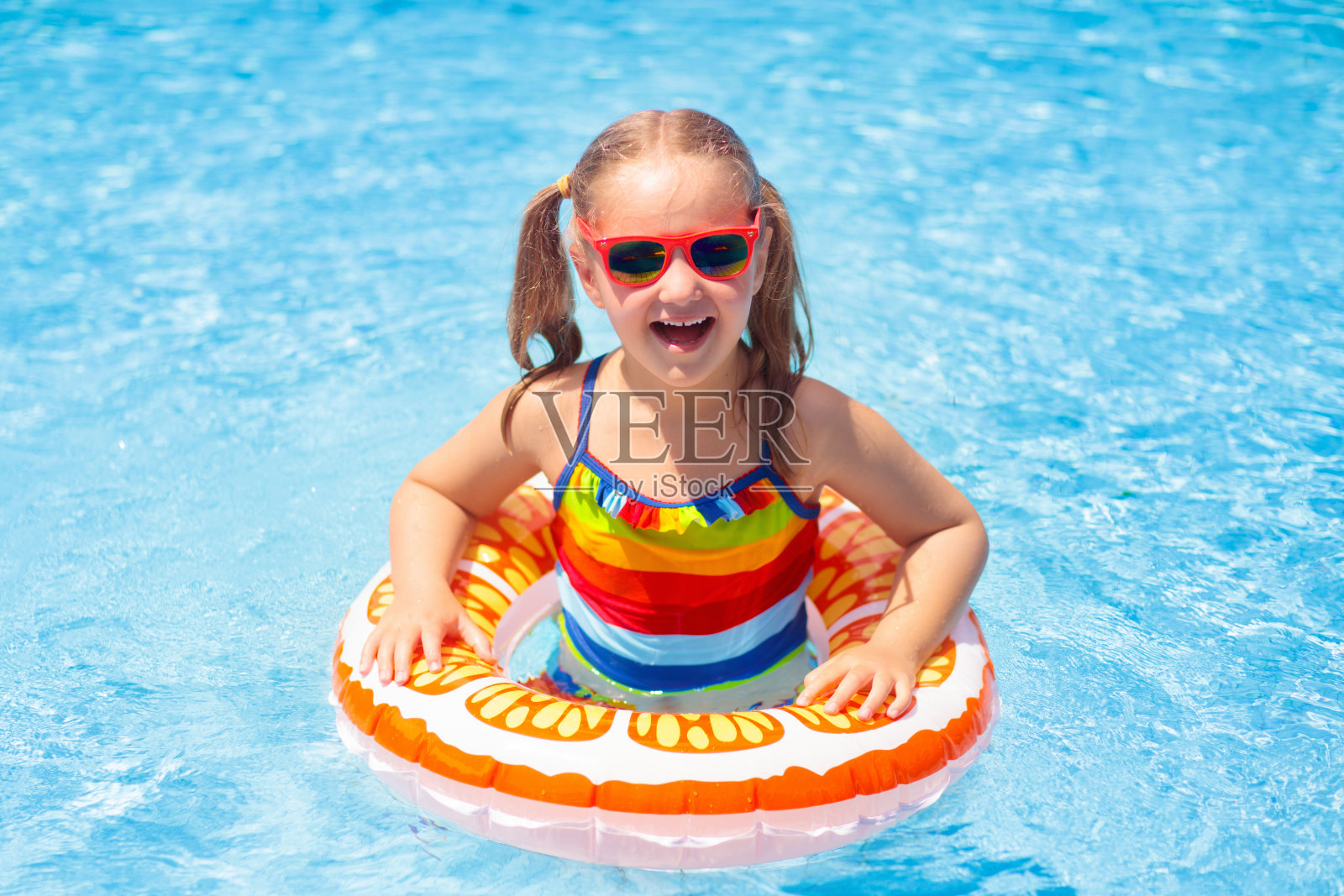 孩子在游泳池的玩具环上。孩子们游泳。照片摄影图片