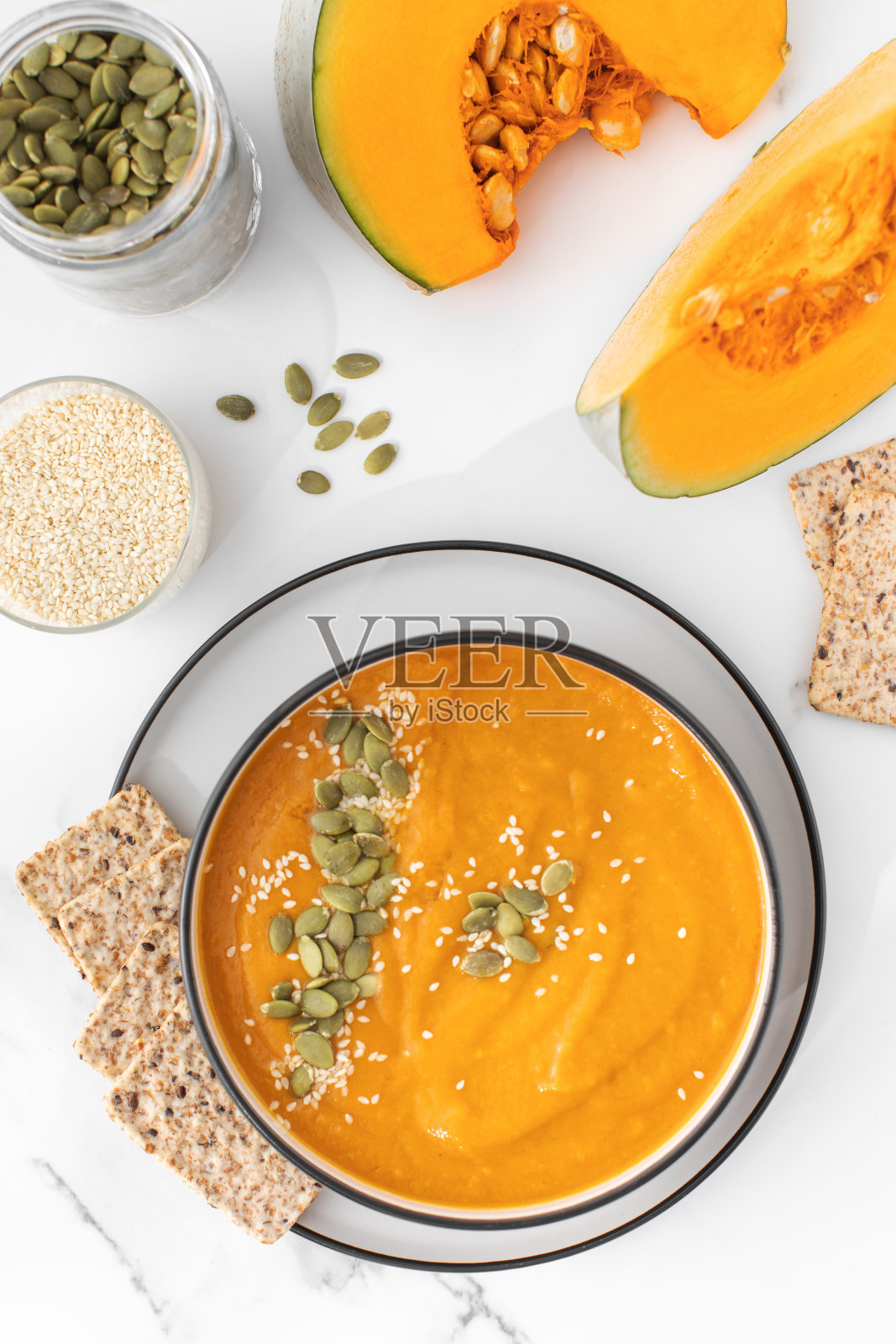 有南瓜汤泥、南瓜和芝麻的盘子。秋季菜单。照片摄影图片