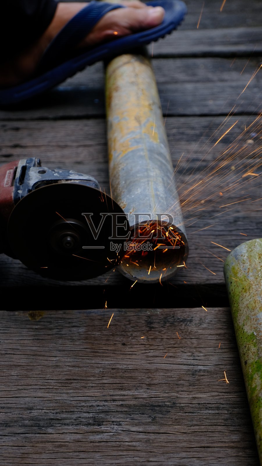 一个人用磨床在一块木头上，焊接火把作为手臂照片摄影图片