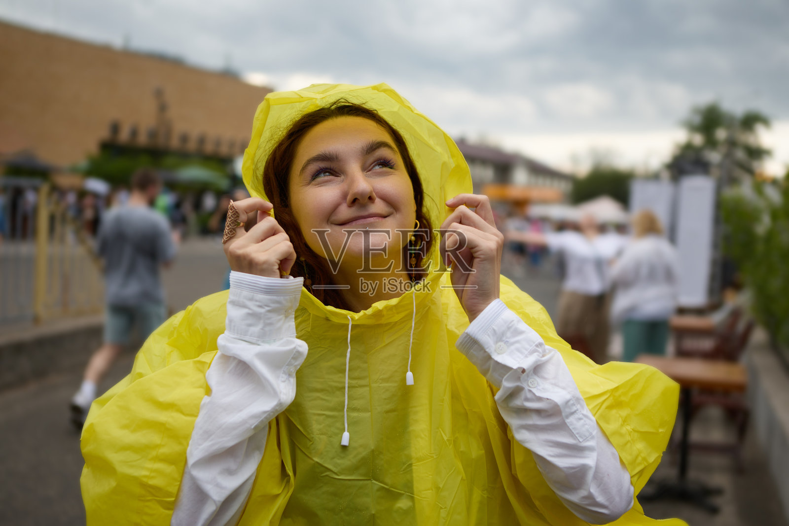 夏日节日里穿着雨衣的开朗的年轻女子。在户外公共活动中享受雨天的女性画像照片摄影图片