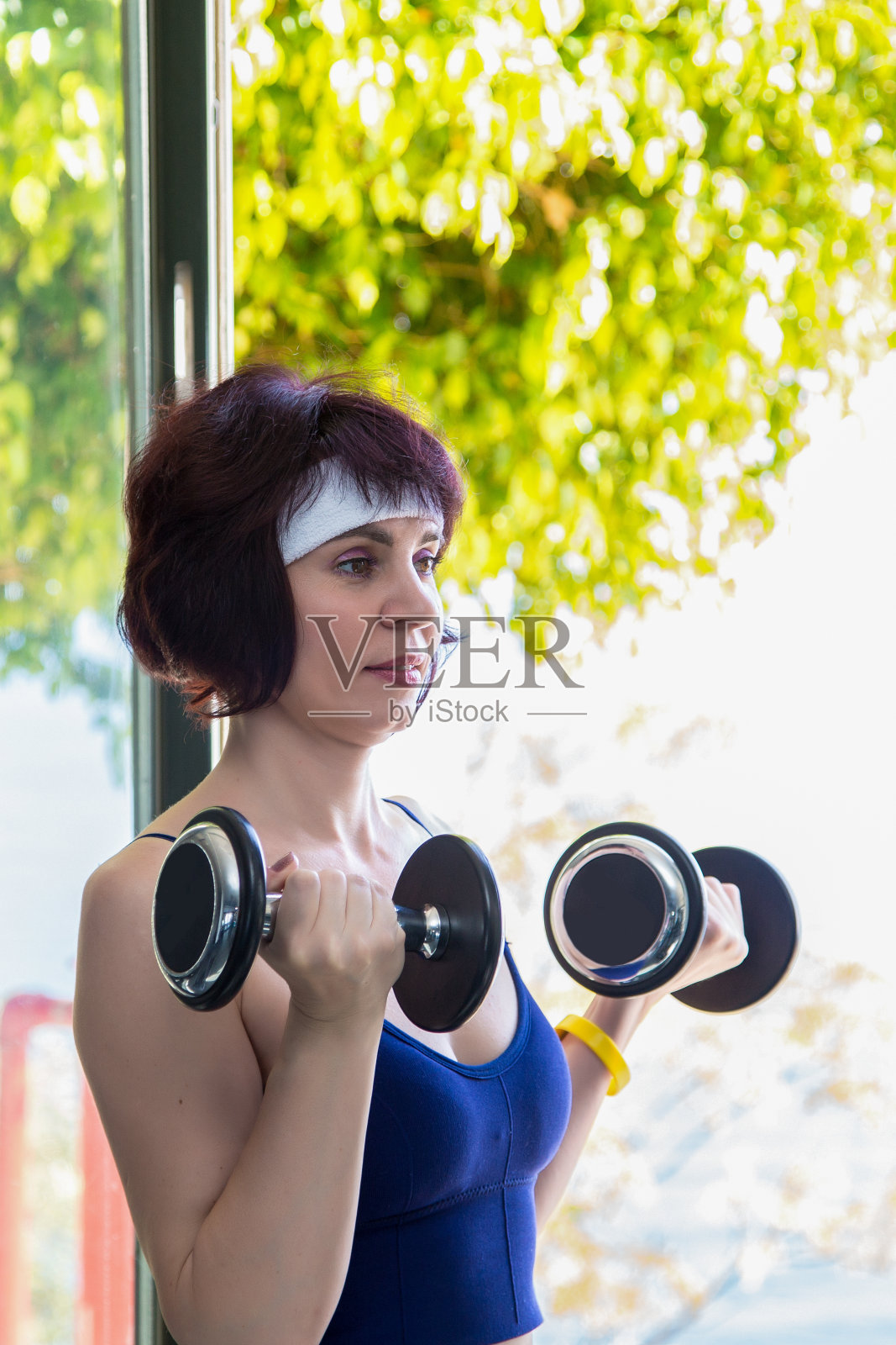 一位年轻的母亲在休完产假后用哑铃锻炼，以保持身材照片摄影图片