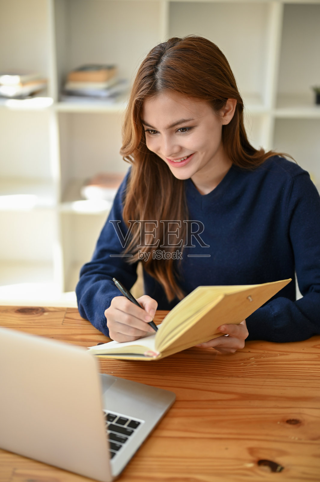 一个美丽的亚洲女大学生在她的书上做笔记的肖像照片摄影图片