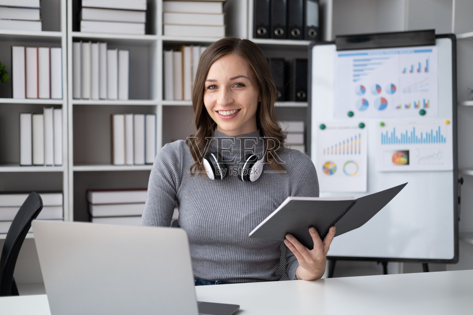 年轻聪明的女商人手里拿着笔记本工作的肖像。照片摄影图片