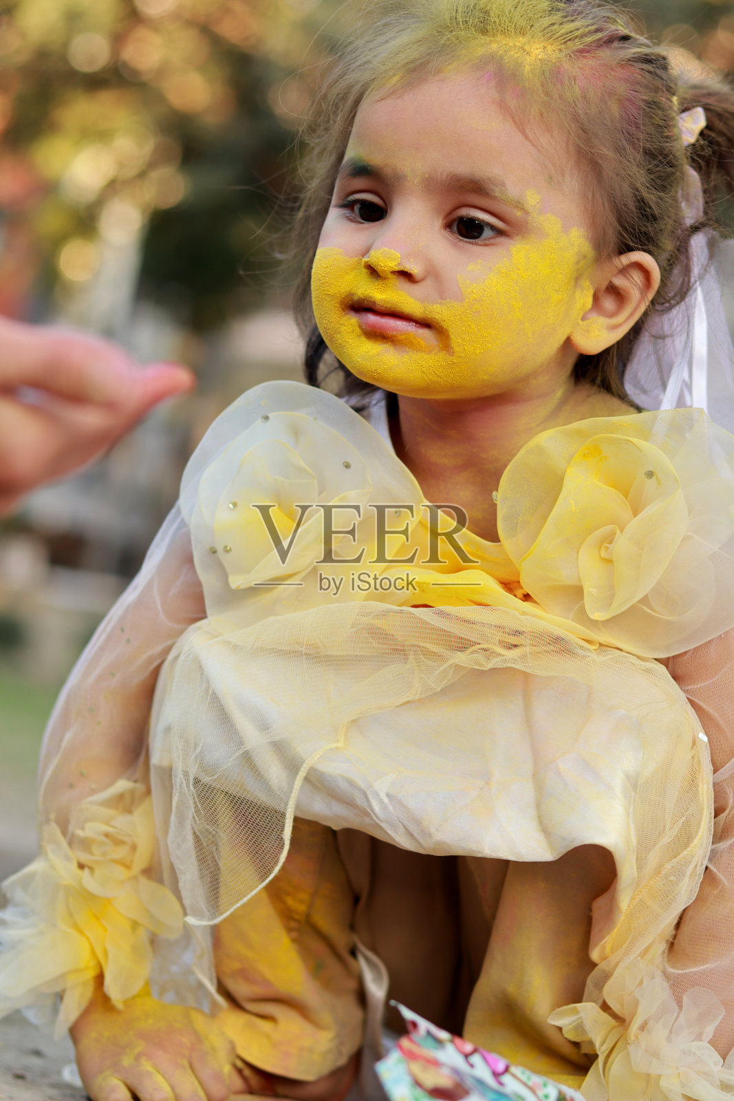 可爱的女婴坐在公园里享受洒红节的色彩照片摄影图片