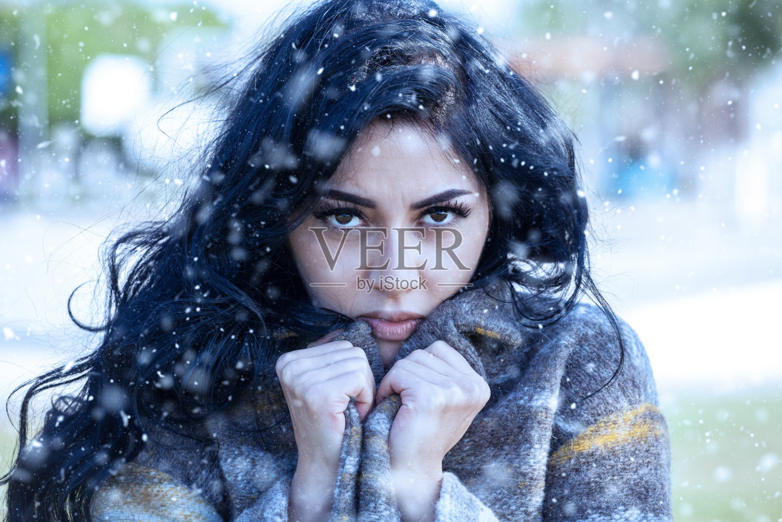 一个下雪的秋日公园里裹着围巾的年轻女子。照片摄影图片