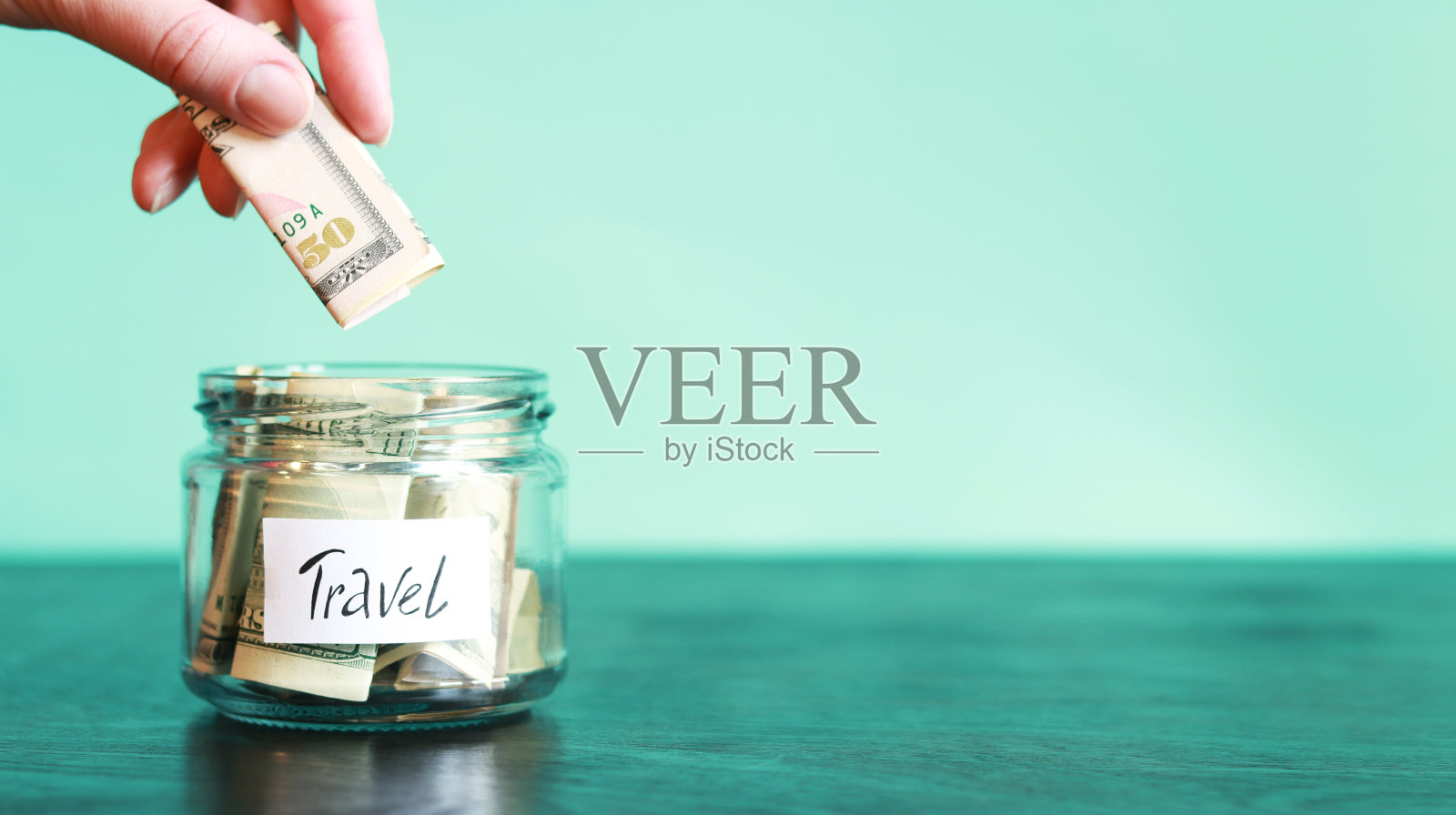 存钱罐里有旅行用的钱。女人往扑满里放了更多的钱照片摄影图片