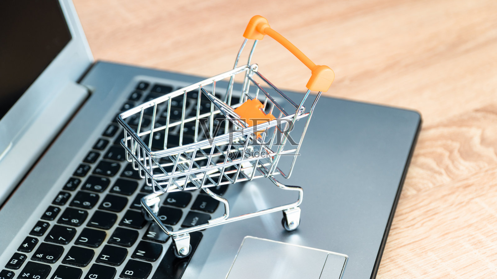 网上购物的概念。购物车或手推车和笔记本电脑放在桌子上照片摄影图片