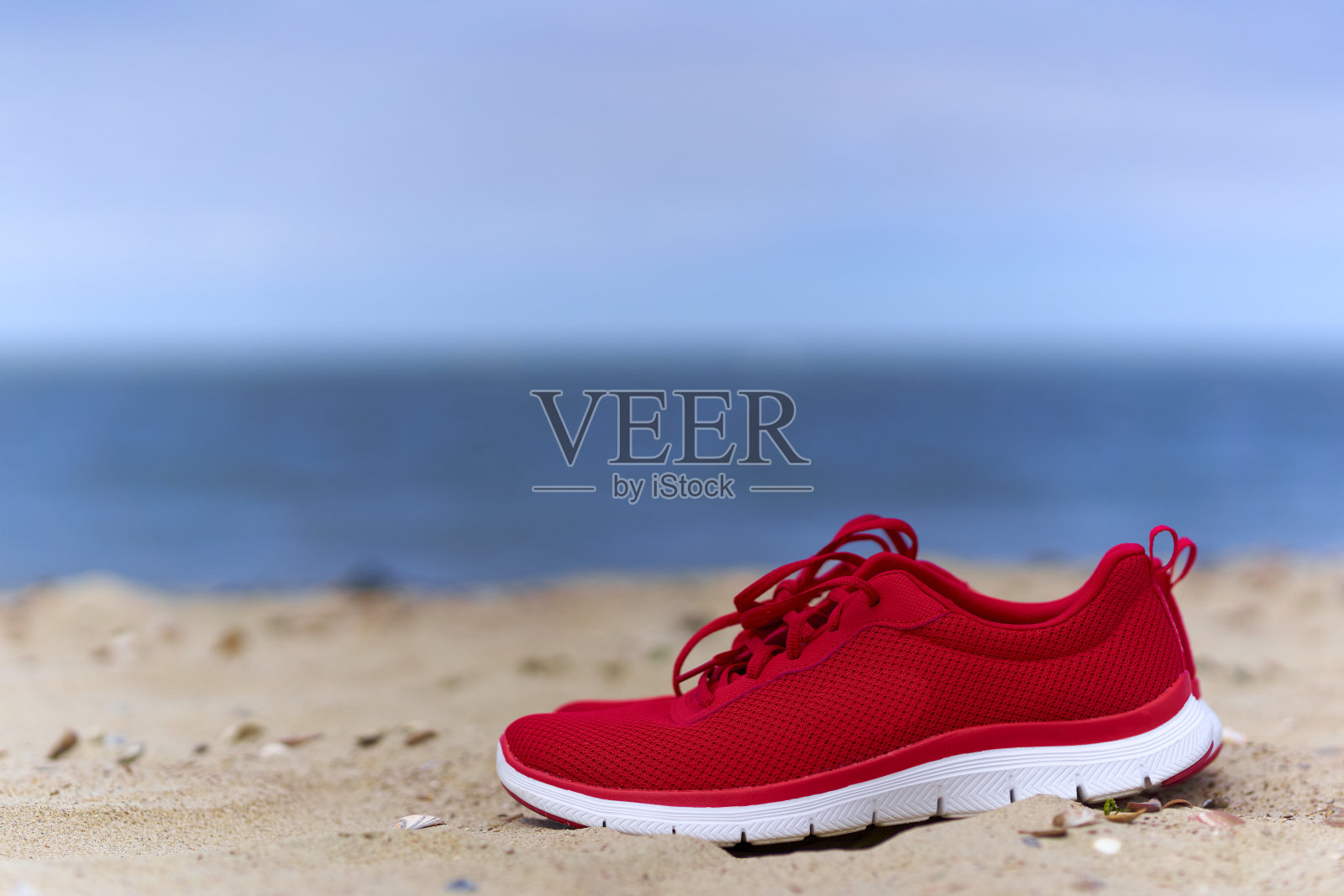 在空旷的沙滩上穿红色女士鞋。适合海上运动和休闲的鞋类。关闭了。照片摄影图片