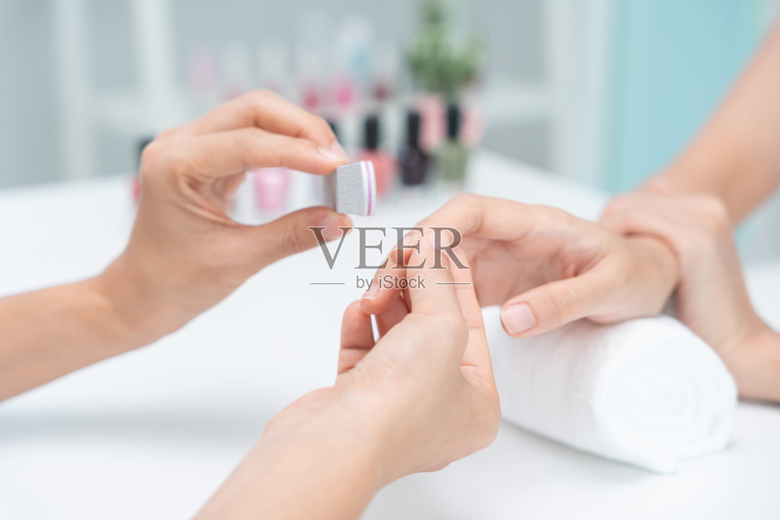 女士在水疗中心接受专业美容师的护理服务。美甲美容院用指甲锉上釉。美甲师让顾客的指甲变得漂亮。身体护理spa护理照片摄影图片