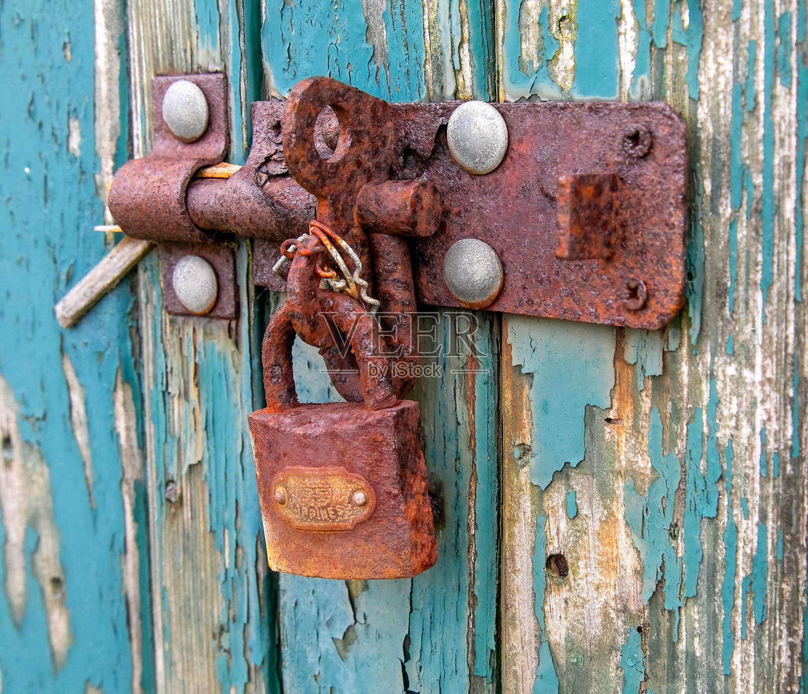 锈迹斑斑的旧挂锁挂在一扇剥落的旧门上照片摄影图片