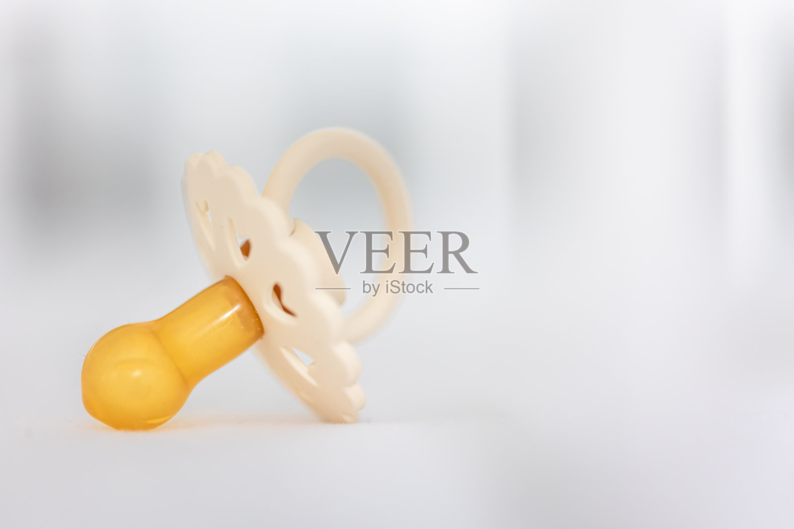 婴儿奶嘴在模糊的白色背景上。照片摄影图片