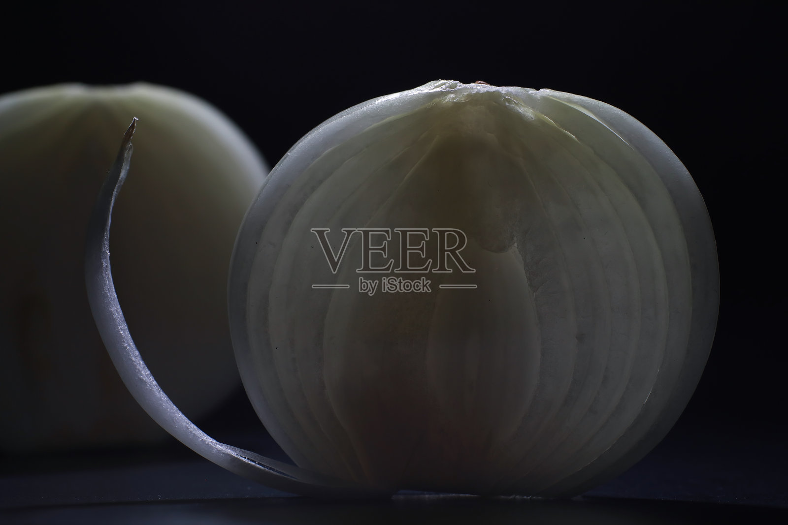 黑色背景的新鲜洋葱。洋葱鳞茎中含有丰富的维生素，有益春天。黑色背景上的洋葱皮。生洋葱片。照片摄影图片