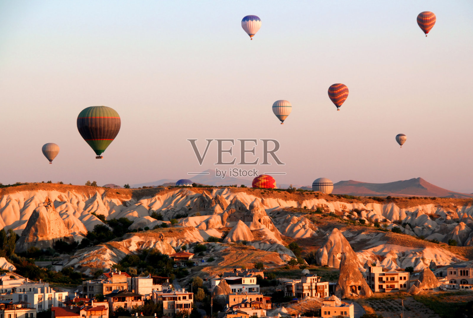 黎明时分，热气球在戈雷梅镇附近的卡帕多西亚山谷上空飞行照片摄影图片