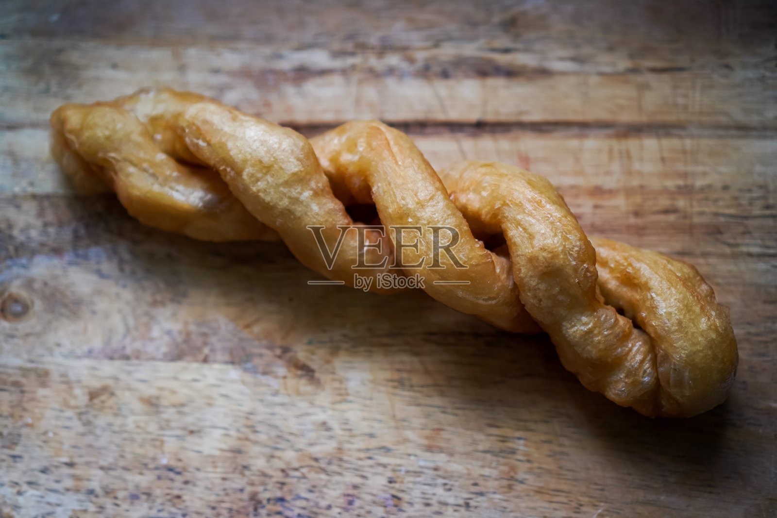 一张特写照片显示了一个大螺旋形的油炸油条，上面放着豆浆。照片摄影图片