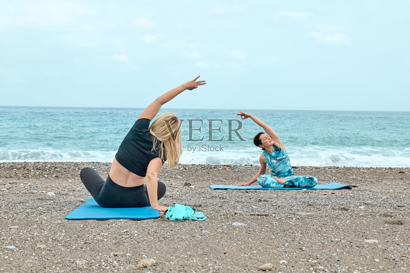 夏季普拉提训练。一群妇女在海边练习瑜伽。瑜伽静修锻炼，身心健康在海边。照片摄影图片