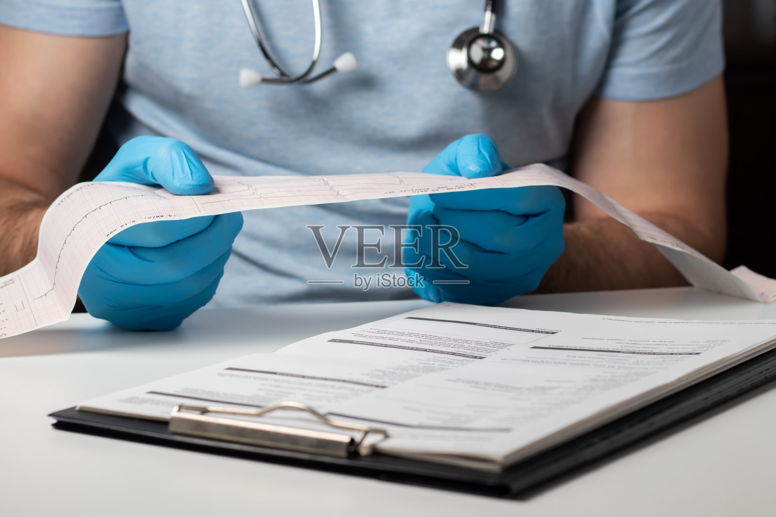 医生的手握着病人旁边的心电图结果。照片摄影图片