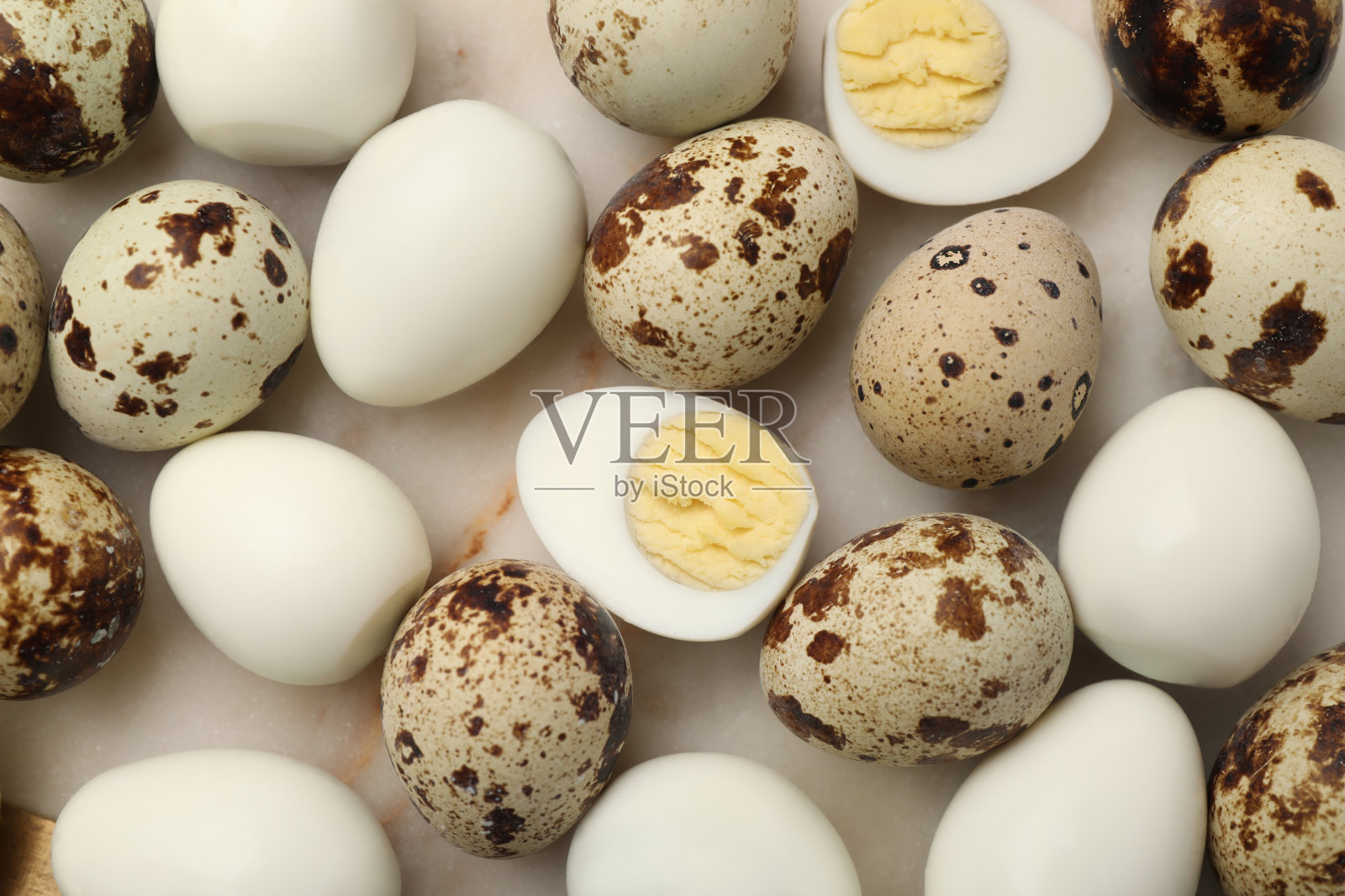 未去皮和去皮的煮熟鹌鹑蛋，放在浅色的桌子上，平躺着照片摄影图片