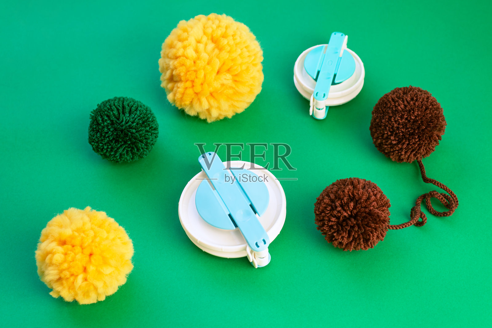 为绒球制作和几个彩色绒球周围的绿色背景的框架的特写。照片摄影图片