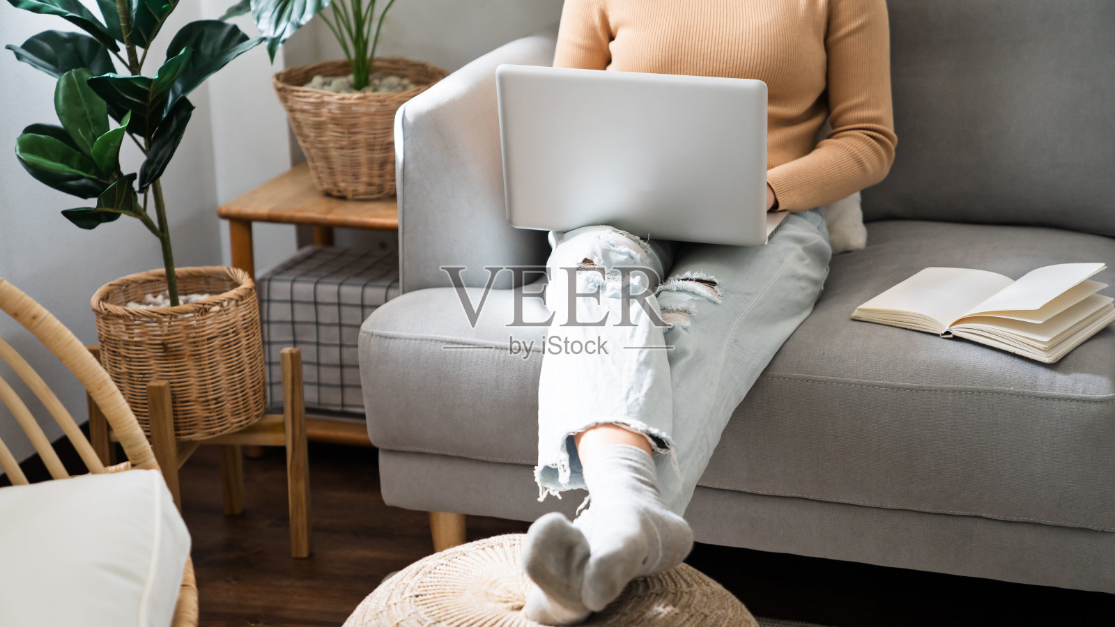 在家里工作年轻的亚洲妇女在笔记本电脑上工作，而坐在客厅。在隔离期间在家工作照片摄影图片