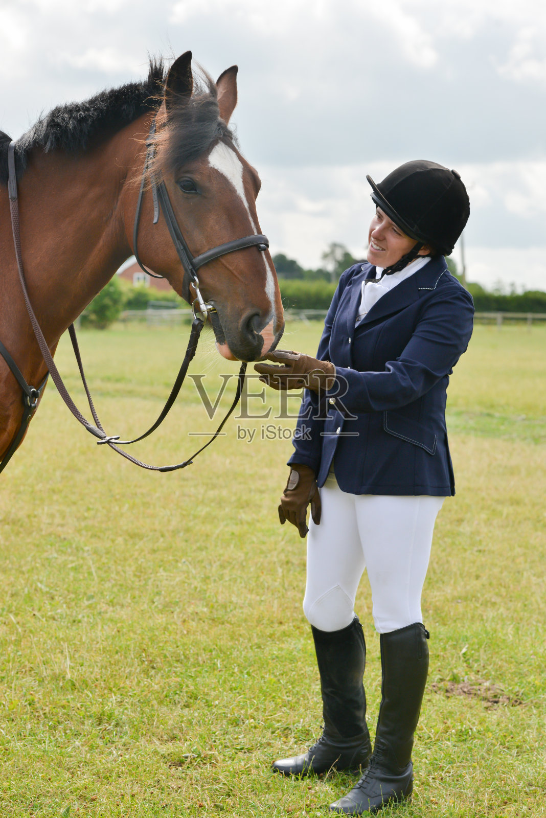 在英国乡下，年轻漂亮的女骑手和她的栗色马一起站在户外，等待参加比赛。照片摄影图片