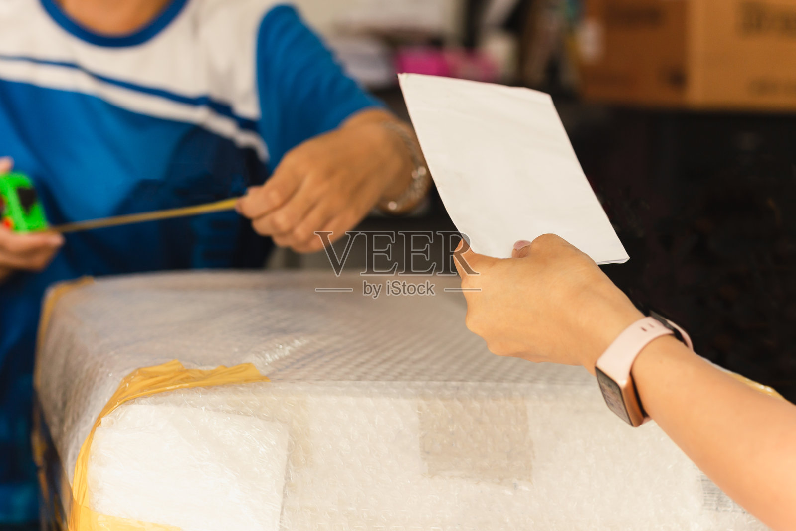 一名妇女从邮局工作人员手中接过包裹。照片摄影图片