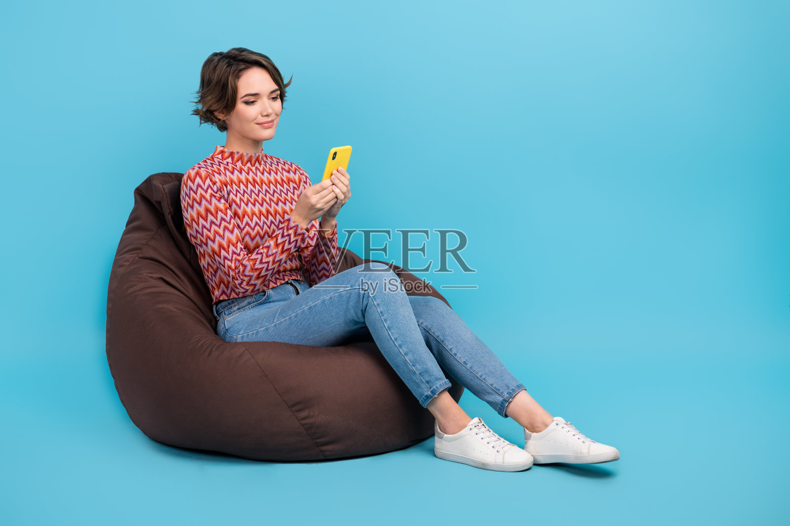 全身照片可爱甜美的女人穿着印花顶豆袋聊天电报facebook空白空间孤立的蓝色背景照片摄影图片