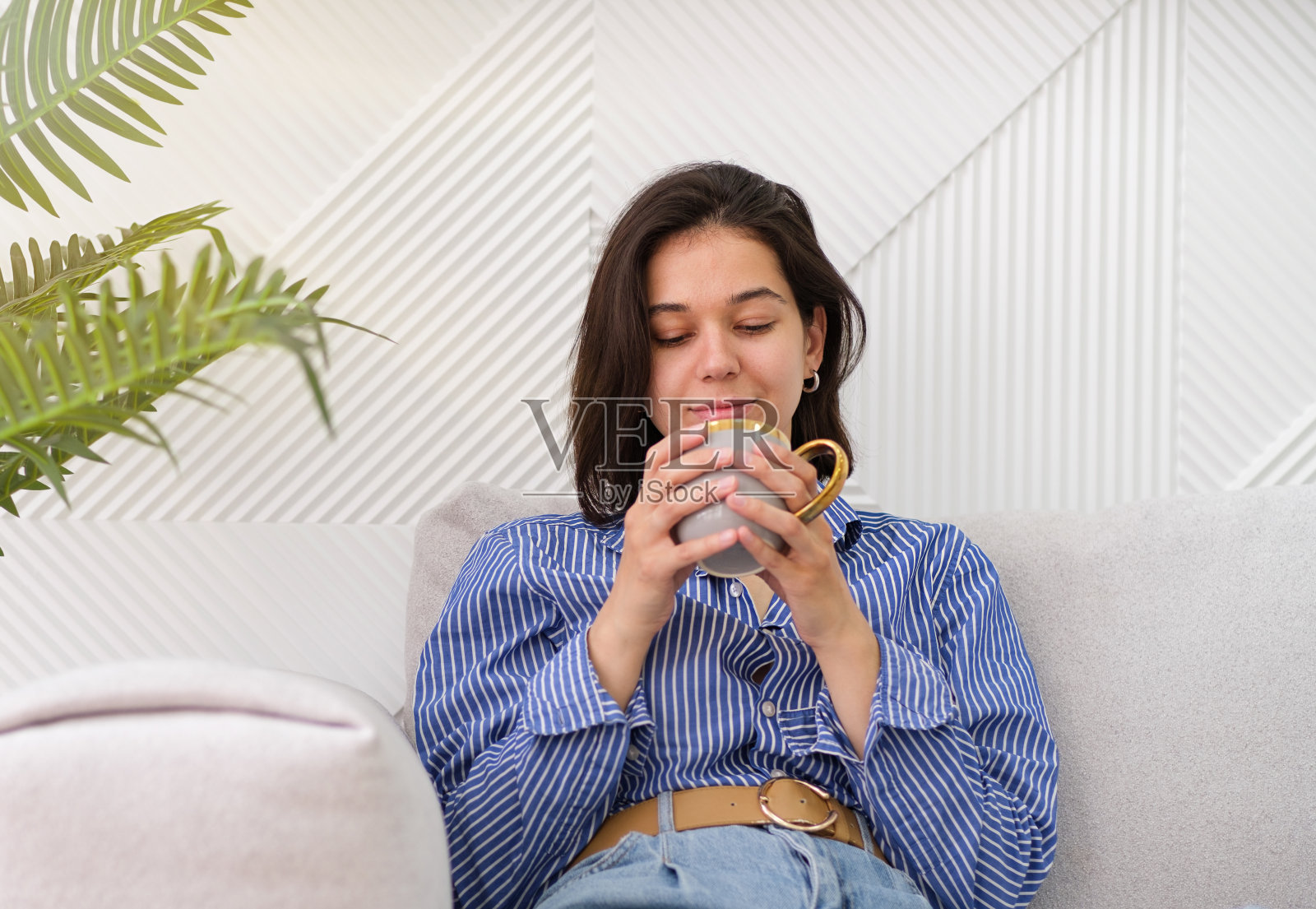 快乐的女人捧着一杯咖啡，女性的寒意带着喝着满足和自我照顾照片摄影图片