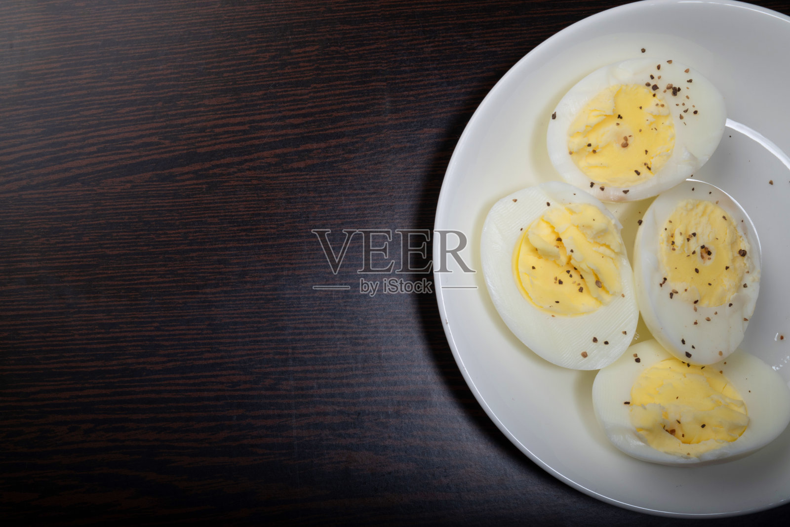 盛在盘子里的煮鸡蛋和调味的黑胡椒照片摄影图片