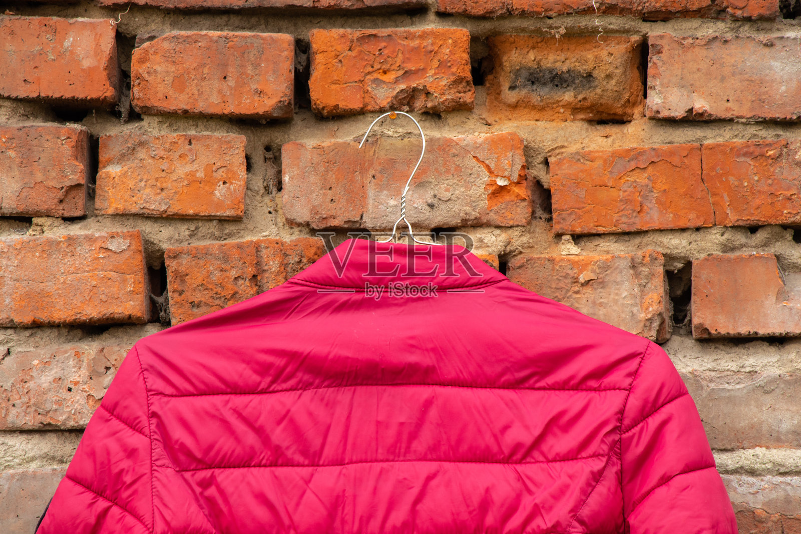 红色女式夹克衫挂在家里墙上的衣架上，在街上，女式夹克衫照片摄影图片